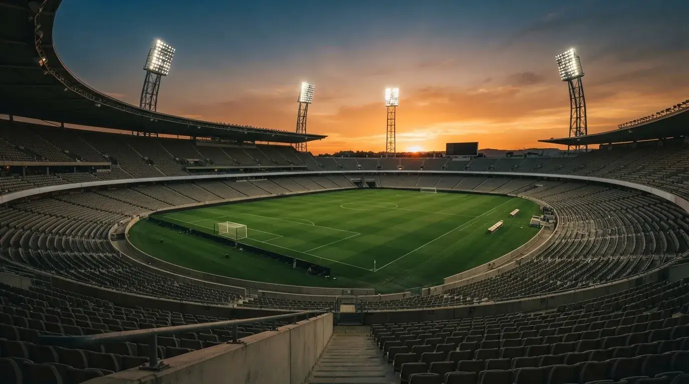 Un estadio de fútbol vacío con torres de iluminación al atardecer
